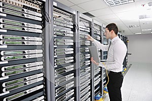 Young engeneer in datacenter server room photo