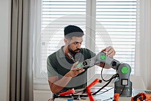 Young engineer building and programming a robotic arm at home.