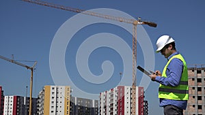 Young engineer with construction equipment, helmet and vest, architect looking and drawing project