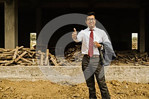 An young engineer in formal suit and pant with portfolio near a construction site feeling confident with fist of success