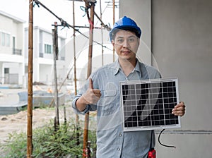 Young engineer in hardhat and walkie talkie lift finger thumbs up while holding solar cell panel, present a source of energy to