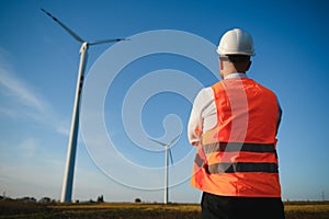 Young engineer man looking and checking wind turbines at field