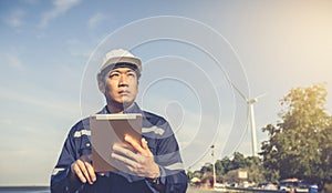 Young engineer man looking and checking wind turbines at field outdoor