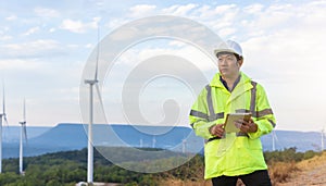 Young engineer man looking and checking wind turbines at field outdoor