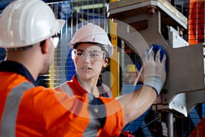 Young engineer man and woman talking and explaining about robot arms technology intelligence and innovation at factory.