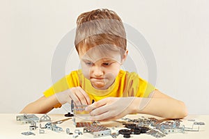 Young engineer plays with mechanical kit at table