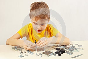 Young engineer plays with mechanical starter kit at table