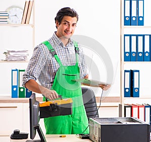Young engineer repairing broken computer at the office