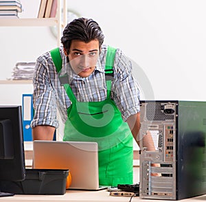 Young engineer repairing broken computer at the office