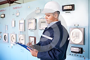 Young engineer taking notes at control room