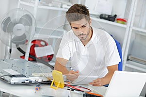 Young engineer taking notes while developping new induction hobs photo