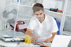 Young engineer taking notes while developping new induction hobs photo
