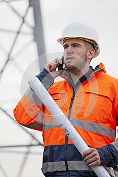 Young engineer talking on smart phone in front of an oil rig or construction site