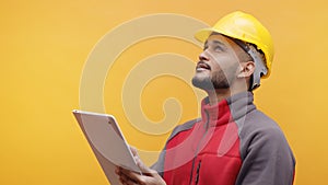 A Young Engineer Wearing Yellow Safety Helmet Holding A Tablet In His Hand