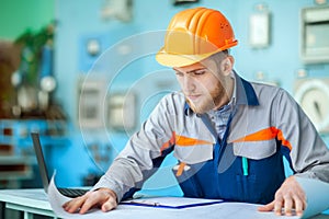 Young engineer working with blueprint at control room