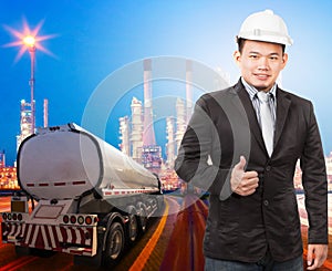 young engineering man with safety helmet standing against beautiful lighting of oil refinery plant in heavy petrochemical