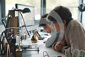 Young engineering students using a 3D printer