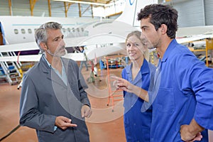 Young engineers with wrench fixing part jetliner