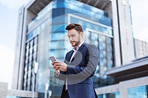 Young enterpreneur browsing internet on smartphone in city center