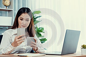 Young enthusiastic businesswoman using smartphone and laptop in office.