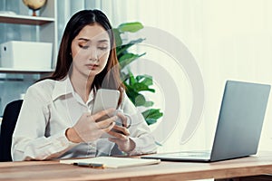 Young enthusiastic businesswoman using smartphone and laptop in office.