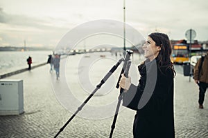 Young enthusiastic female photographer setting up lightweight carbon travel tripod for sunset/sunrise log exposure still shot