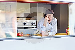 Young entrepeneur talking on the phone at his takeaway food stal photo