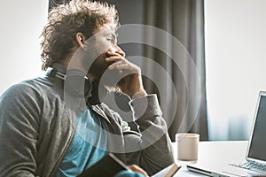 A young entrepreneur brings down accounting. The man takes notes in a notepad and looks at the computer screen sitting