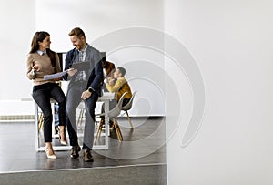 Young entrepreneur couple sitting together on a desk and using digital tablet in the modern office