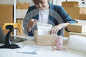Young entrepreneur packing online order product for shipping.