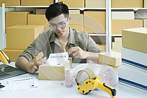 Young entrepreneur packing online order product for shipping.