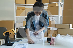 Young entrepreneur packing product in mailing box for shipping.