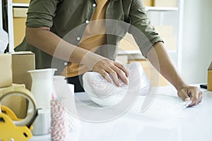 Young entrepreneur packing product in mailing box for shipping..