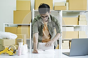 Young entrepreneur packing product in mailing box for shipping..