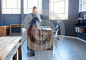 Young entrepreneur using a tablet and talking on his cellphone