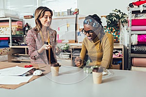 Young entrepreneur women, or fashion designers working in atelier and making short breakfast break at work