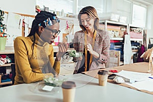 Young entrepreneur women, or fashion designers working in atelier and making short breakfast break at work