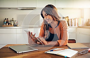 Young entrepreneur working in her kitchen using a digital tablet photo