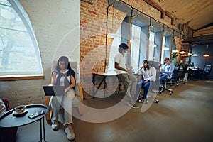 Young entrepreneurs and students in co-working space working and cooperating. Cozy, comfortable professional atmosphere