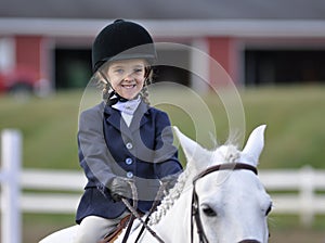 Young equestrian girl on white horse