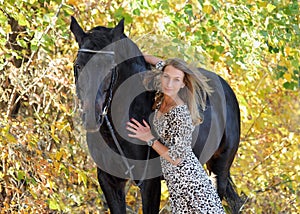Young equestrian woman walking horse in autumn park