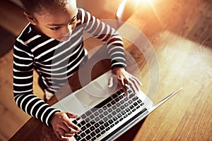 Young ethnic black girl typing on a laptop