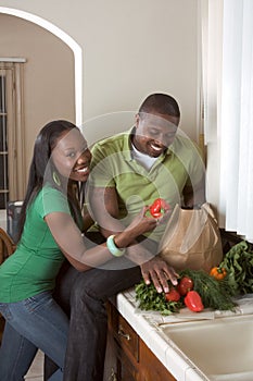 Young ethnic couple on kitchen sorting groceries