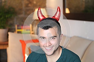 Young ethnic man with devil horns at home