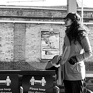 Young Ethnic Woman Standing Alone Waiting For A Train On Clapham Junction Station Platform