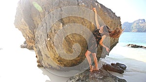 young european brunette girl poses by rock on sea coast