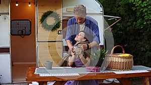 Young, european couple travelling, camping,living in trailer. Portrait of a woman dring a tea outdoors, while man coming