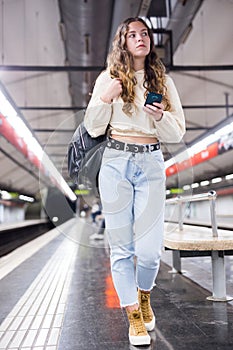 Young european female with mobile waiting the metro