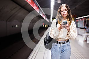 Young european female with mobile waiting the metro