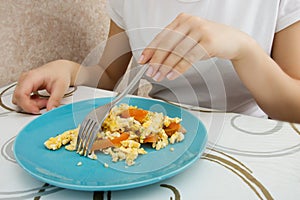 Young European girl with long hair eating eggs with tomatoes